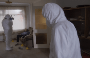 Crime scene investigators in a room with a body on a couch.