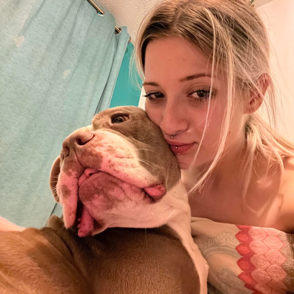 Woman cuddling with her XL Bully dog.