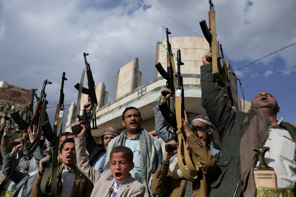 Houthi supporters at a protest in Sanaa, Yemen, holding weapons aloft.