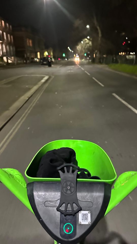 First-person view of riding a Lime e-scooter at night.
