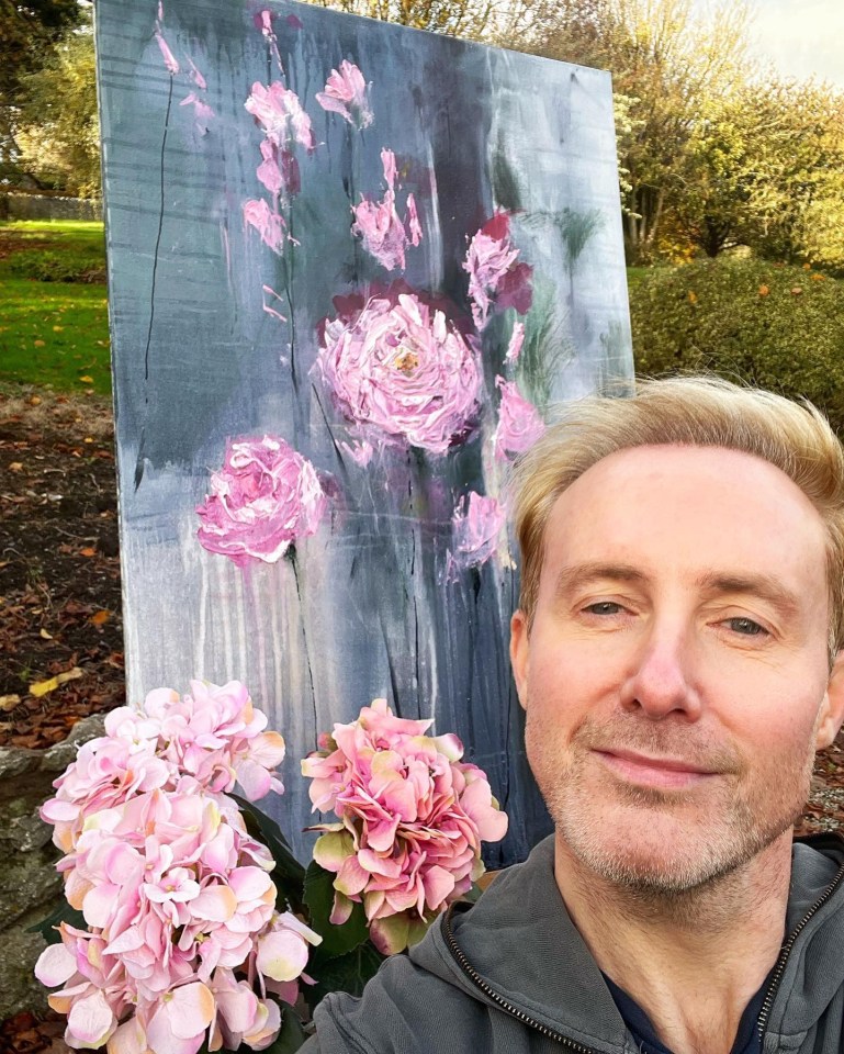 Ian Watkins with a painting of pink flowers and pink hydrangeas.