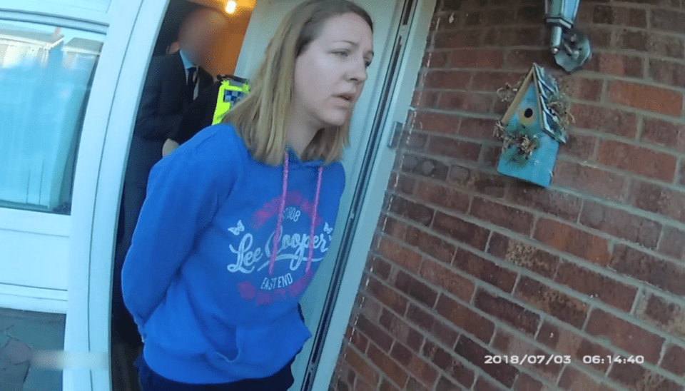 Woman in blue hoodie being arrested at her front door.