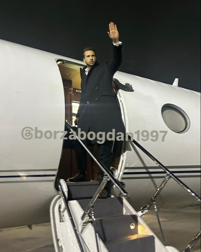 Man waving goodbye from private jet steps.