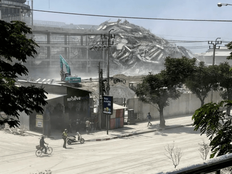 Demolition of a large building, with dust and debris covering the surrounding area.