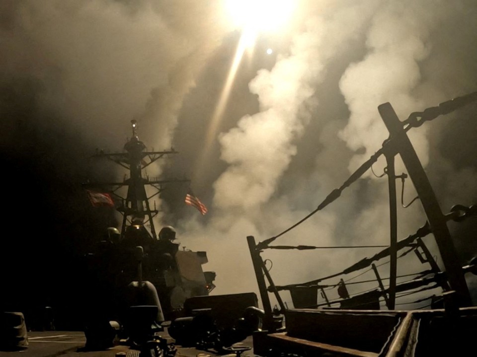 US Navy ship firing missiles in smoky conditions.
