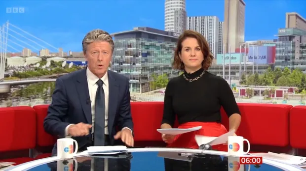 Two news presenters sitting at a desk in a television studio.