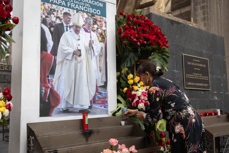 Woman lighting a candle at a memorial to Pope Francis.