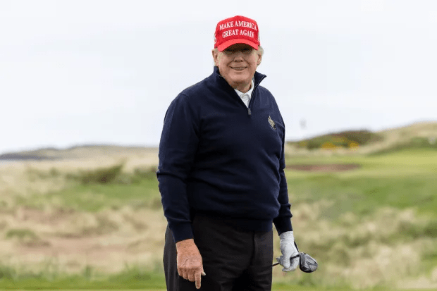 Donald Trump on a golf course wearing a "Make America Great Again" hat.