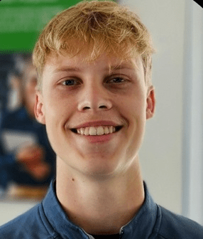 Headshot of a young man with blond hair and a blue jacket.