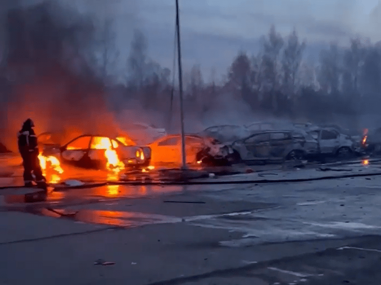 Cars on fire with a firefighter present.
