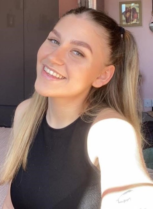 Portrait of a smiling young woman with blonde hair in a ponytail.