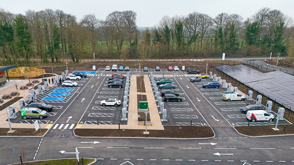 Aerial view of a large electric vehicle charging station with solar panels.