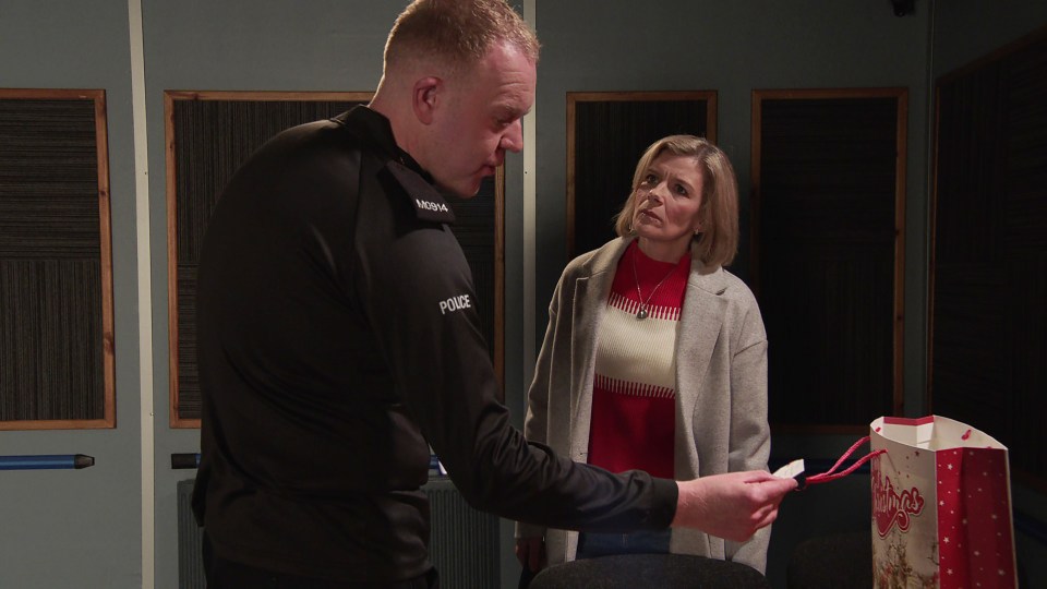 A police officer examining a Christmas gift bag with a woman.