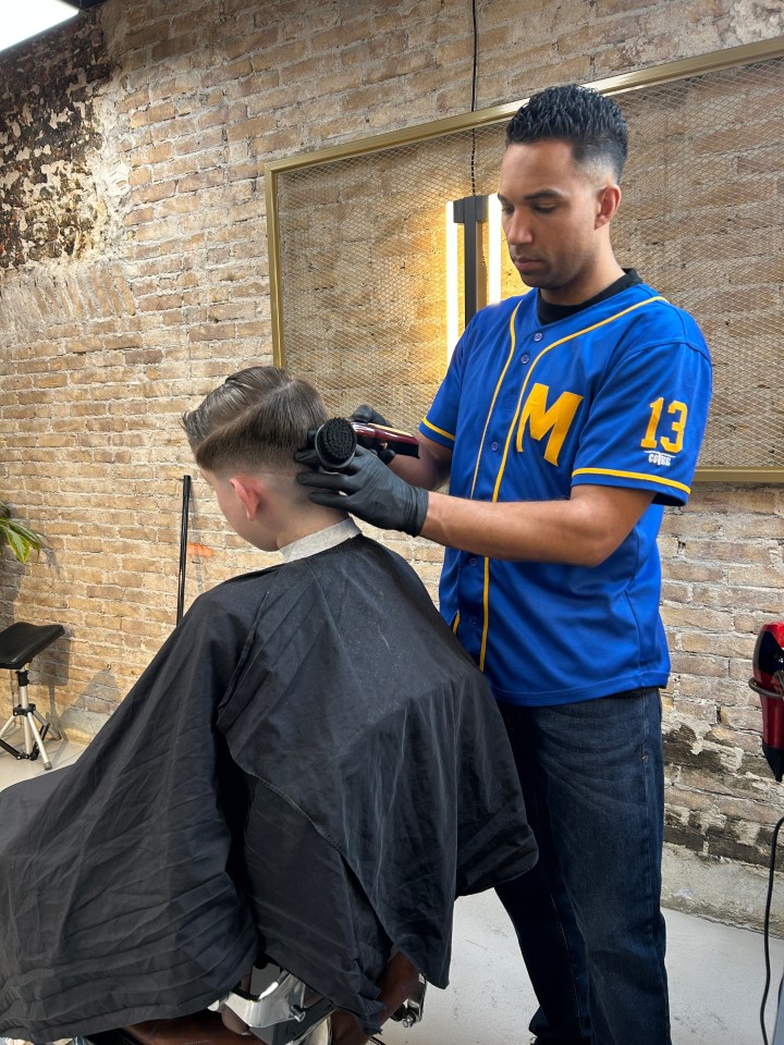 A barber cuts a client's hair.
