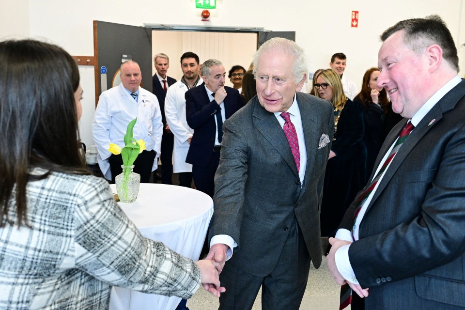King Charles III meeting with scientists and students at a cancer research center.