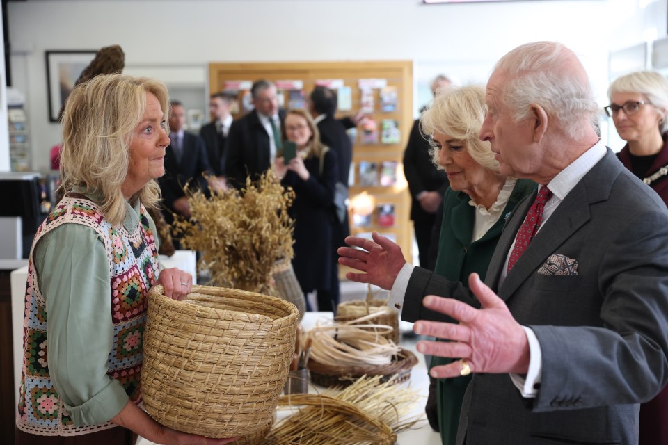 King Charles III and Queen Camilla view willow artwork at an arts center.
