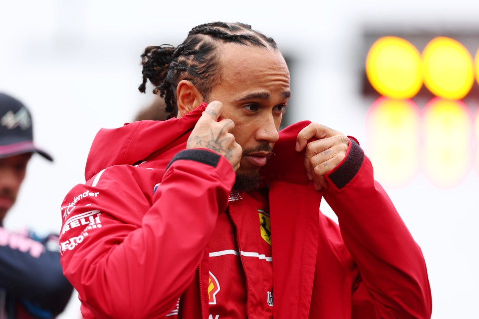 Lewis Hamilton adjusting his red Ferrari jacket.