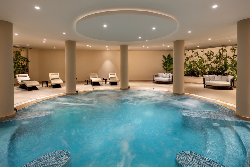 Indoor spa with a circular pool and lounge chairs.