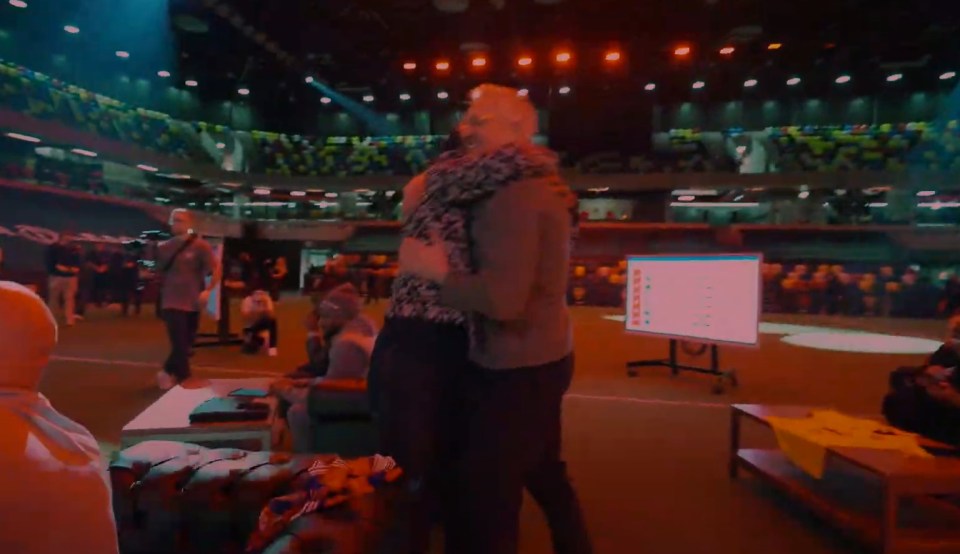 Two people embracing in a large venue.