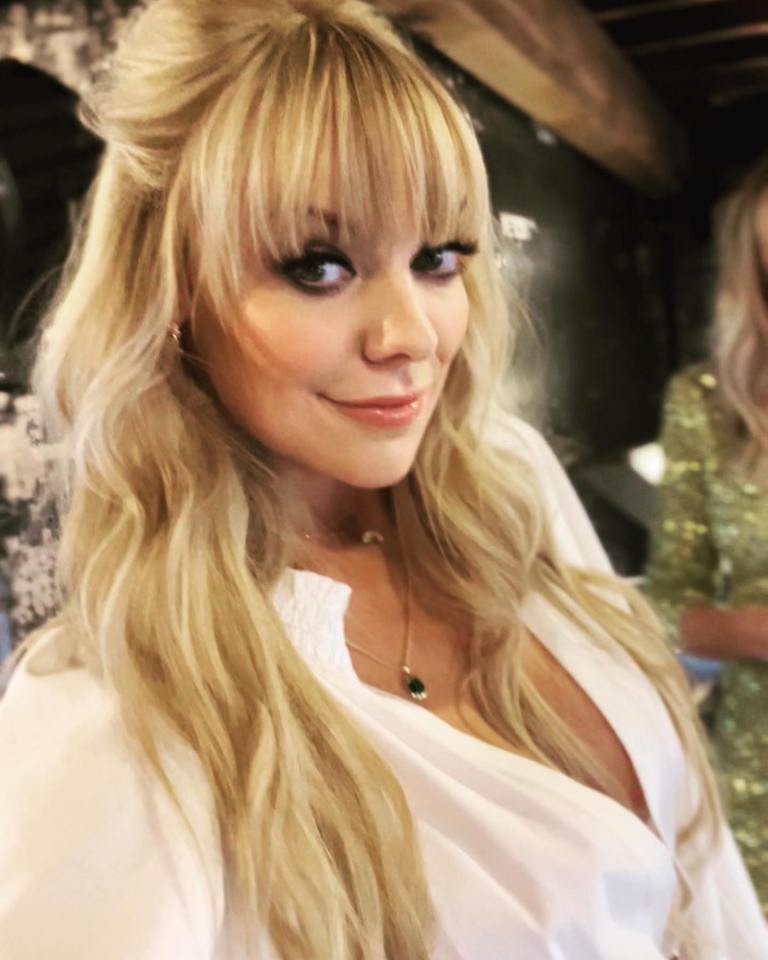 Woman with long blonde hair wearing a white shirt.