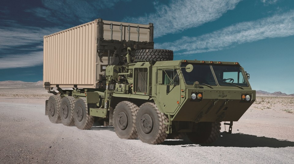 Oshkosh M1075 military truck carrying a shipping container.