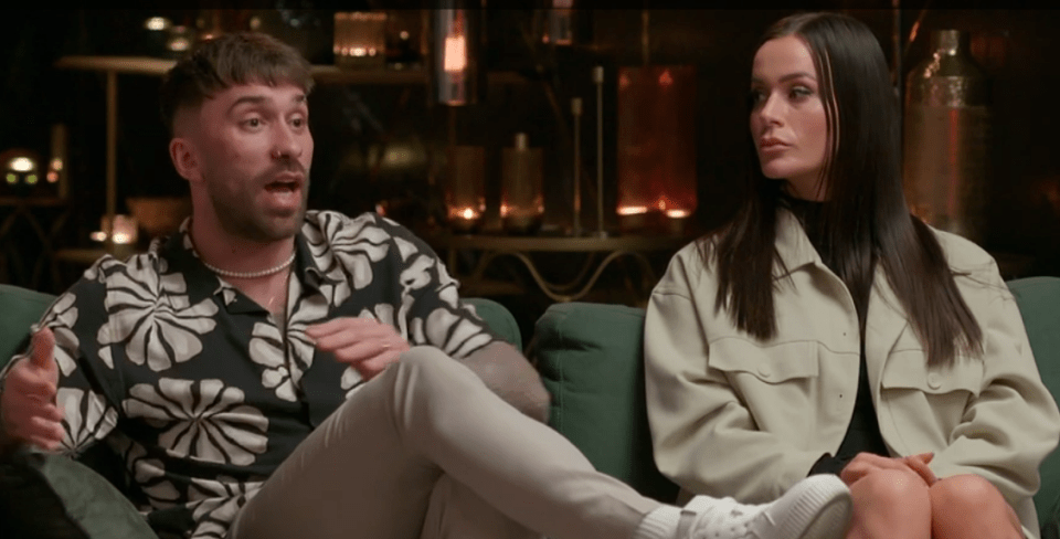 A man and woman sitting on a couch, having a conversation.