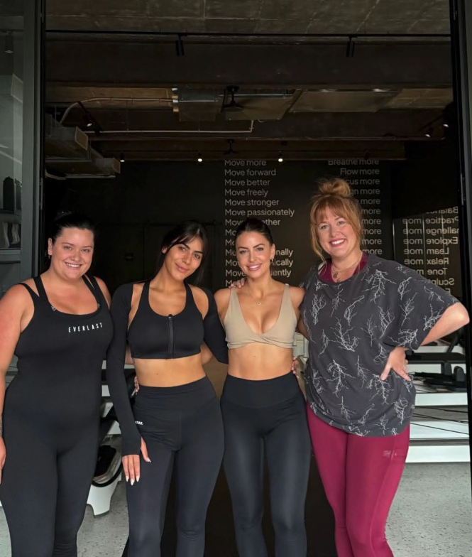 Four women in workout clothes pose for a photo.