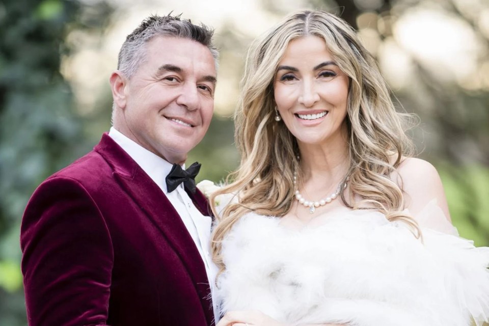 A groom in a burgundy velvet jacket and a bride in a white dress.