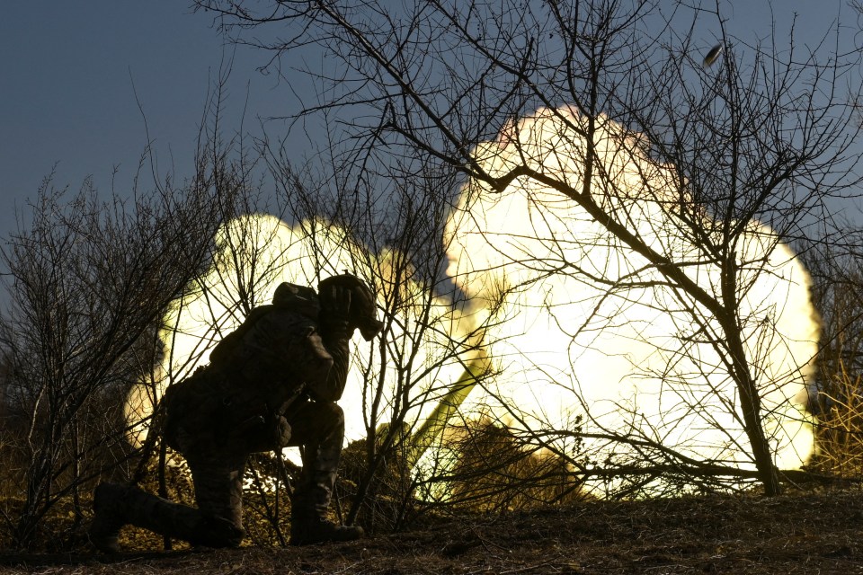 Silhouette of a soldier firing a howitzer.