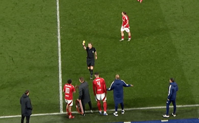 Referee showing a soccer player a yellow card.