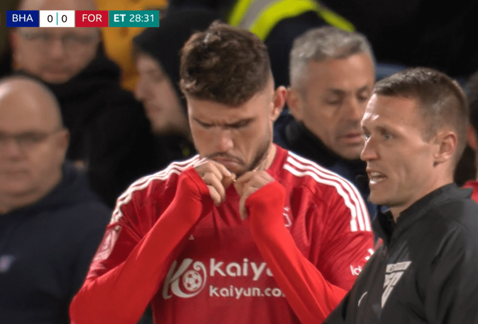 Soccer player adjusting his sleeve while speaking with a coach.