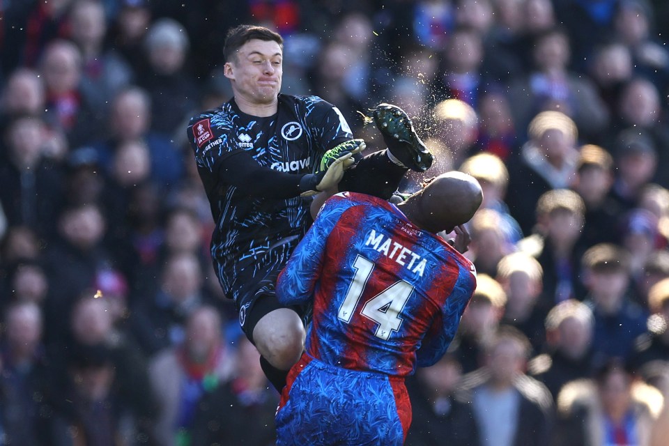 A soccer goalkeeper karate kicks an opposing player in the head.