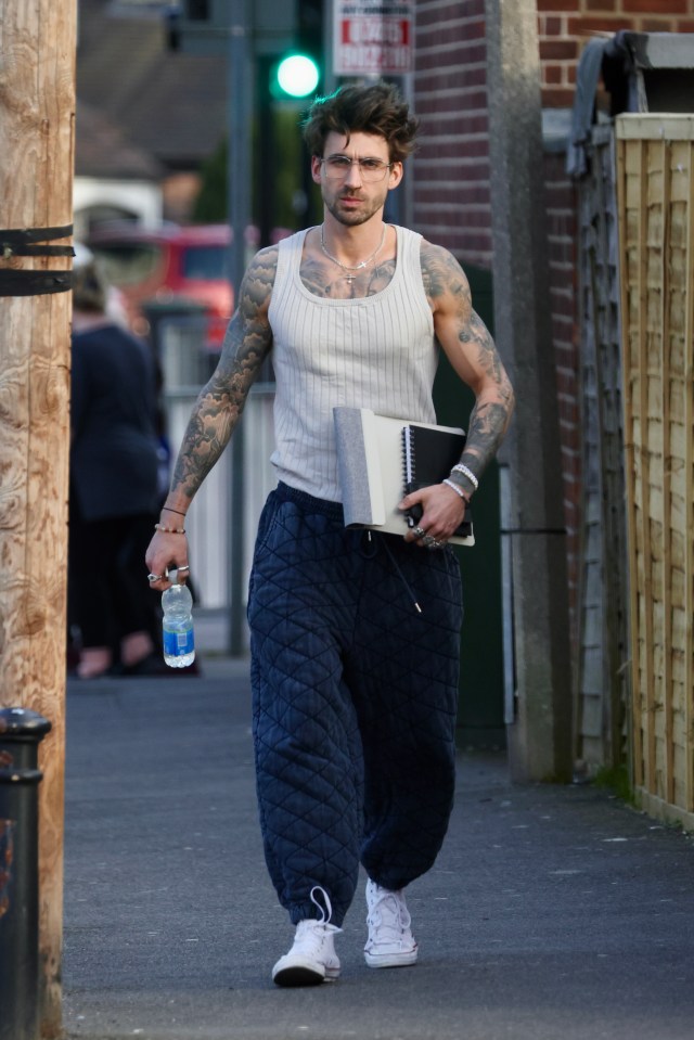 Chris Taylor walking down a street, carrying a notebook and a water bottle.