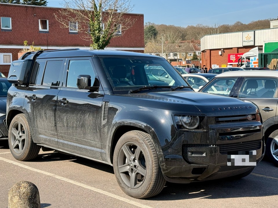 Black Land Rover Defender parked in a parking lot.
