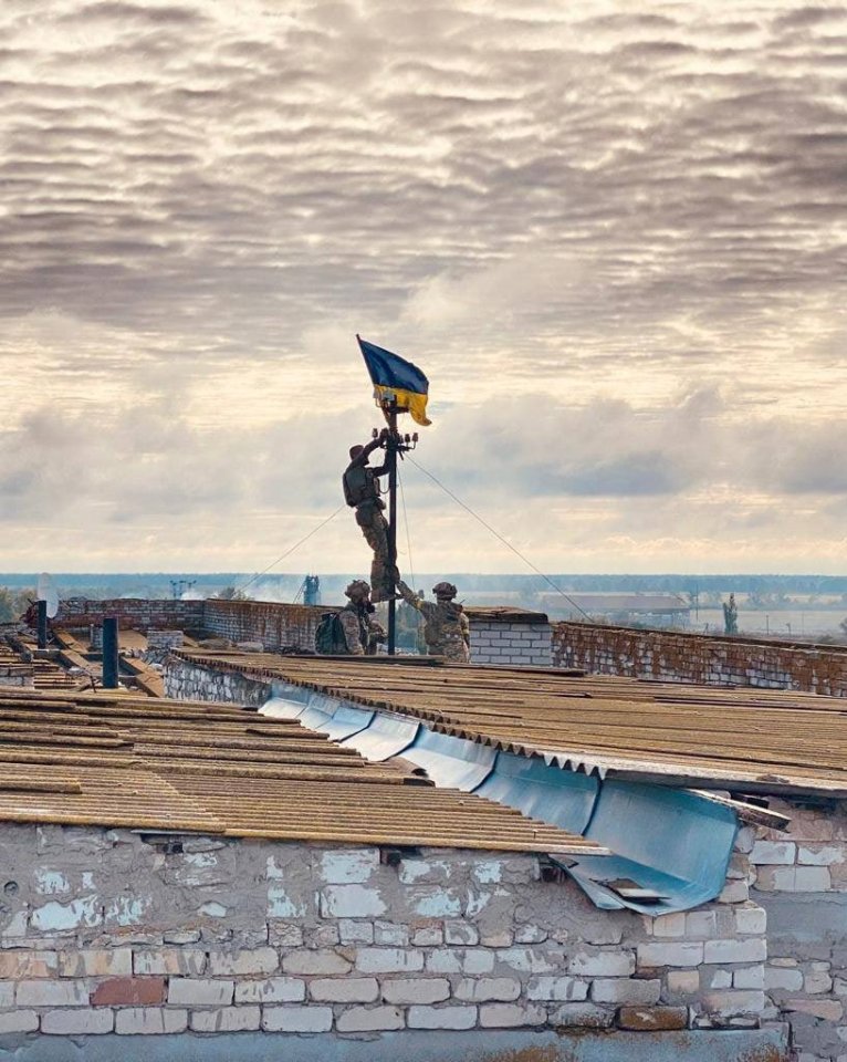Ukrainian soldiers raising a flag on a hospital roof in Vysokopillia.