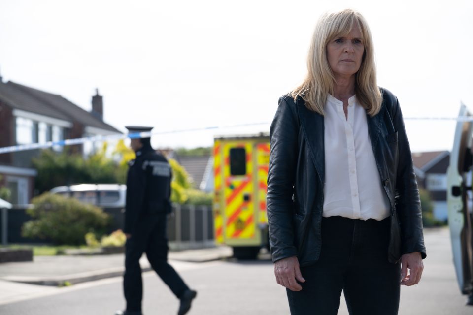 DI Liz Nyles, from the TV show SR1, standing on a residential street.