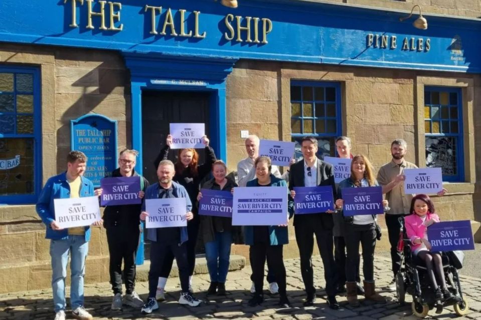 An image collage containing 1 images, Image 1 shows Group of people holding signs that say "Save River City" in front of a pub