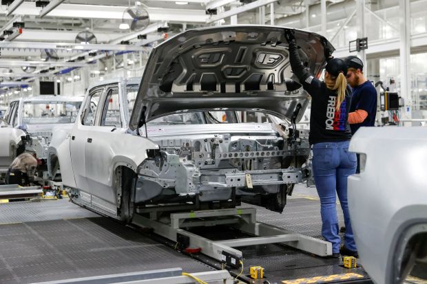 An image collage containing 1 images, Image 1 shows Workers assembling an electric vehicle on an assembly line