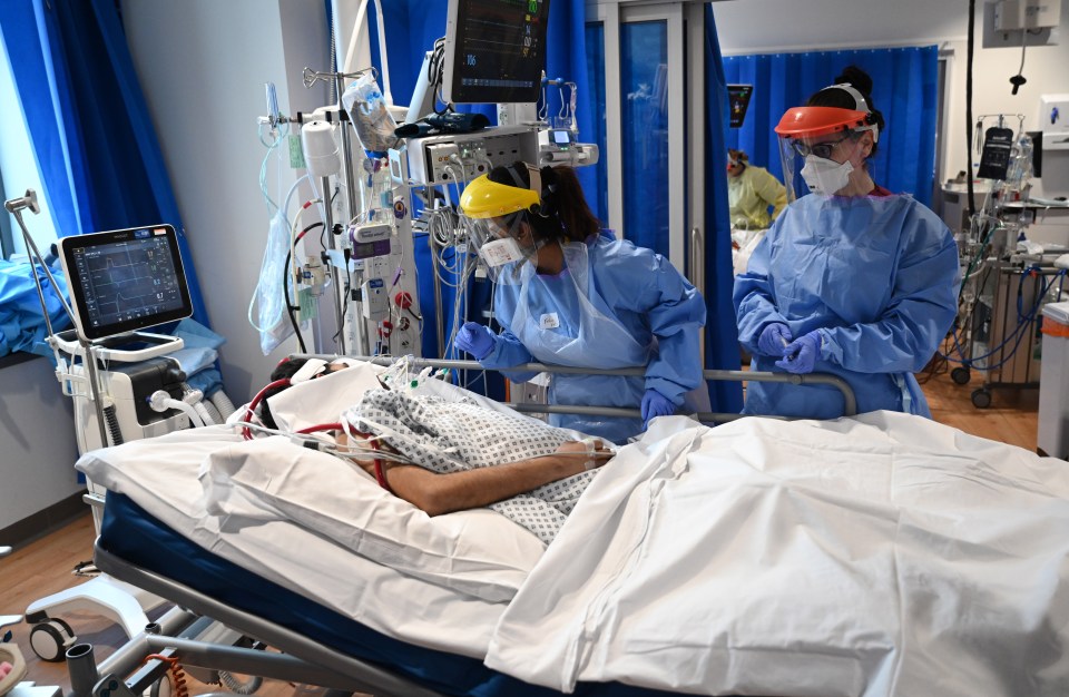 NHS staff in PPE attending to a patient in an intensive care unit.
