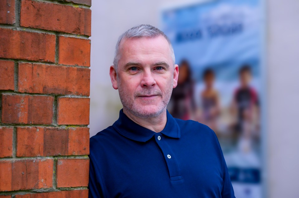 Portrait of a man leaning against a brick wall.
