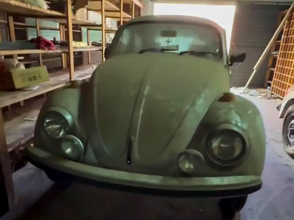 Dust-covered Volkswagen Beetle in a garage.
