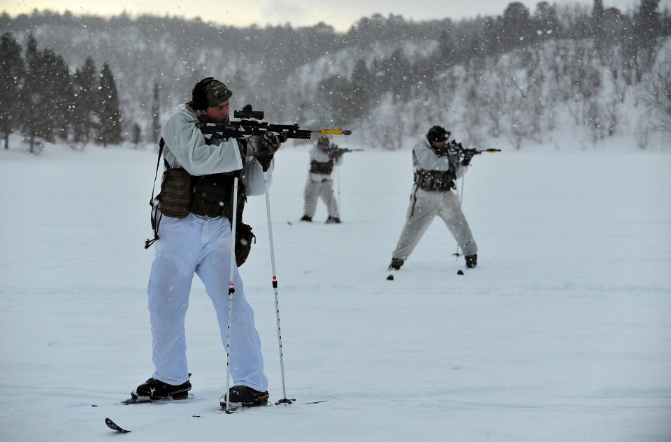 Royal Marines on skis firing rifles during a cold-weather training exercise.