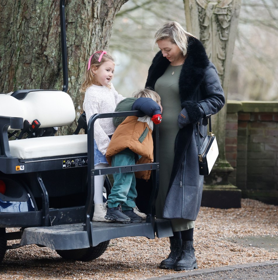 Woman with two young children by a golf cart.