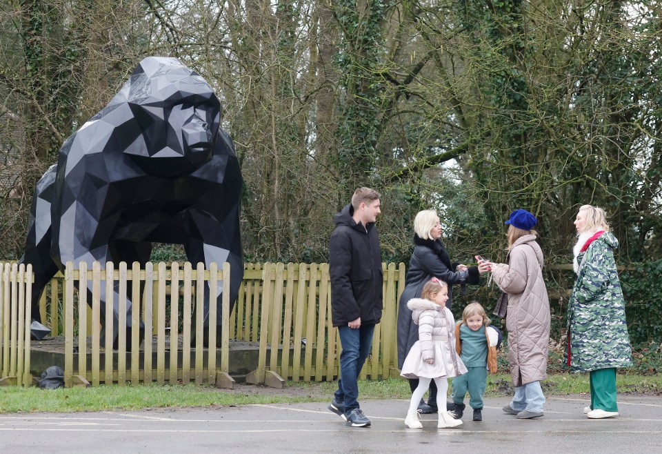 Family with children standing near a large gorilla sculpture.
