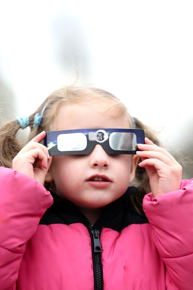 Young girl wearing eclipse glasses.