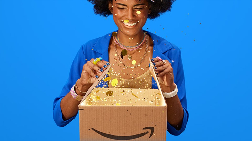 Person opening an Amazon box filled with gold confetti.
