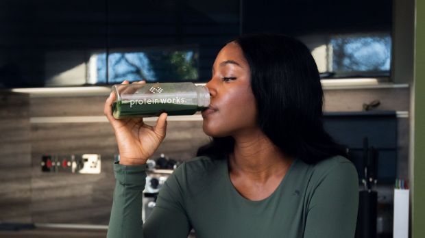 Woman drinking green Protein Works shake.