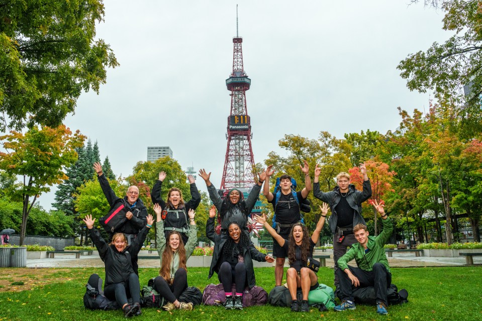 Group photo of Race Across the World season 4 contestants in a park with a tower in the background.
