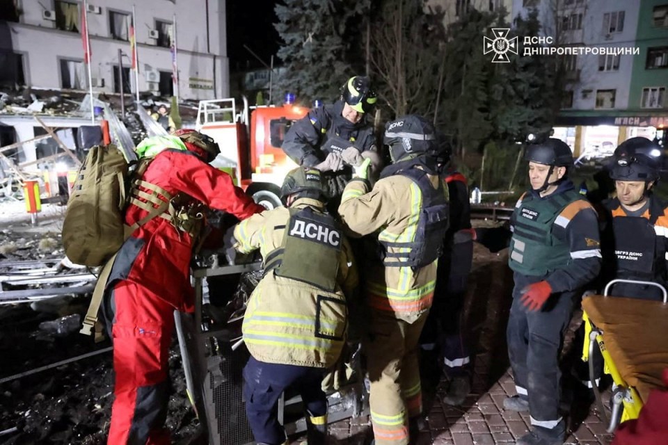 Rescuers carry a wounded person from a damaged building.