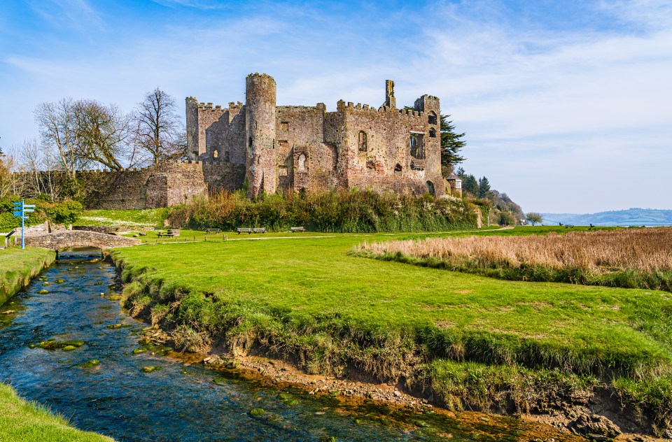 Ruins of Laugharne Castle in Wales, beside a stream.